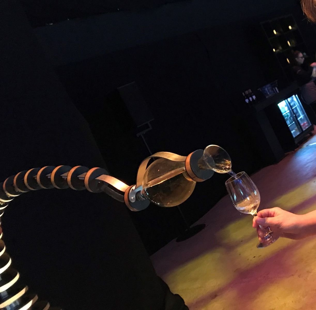 A robotic arm serving a drink at an interactive bar experience