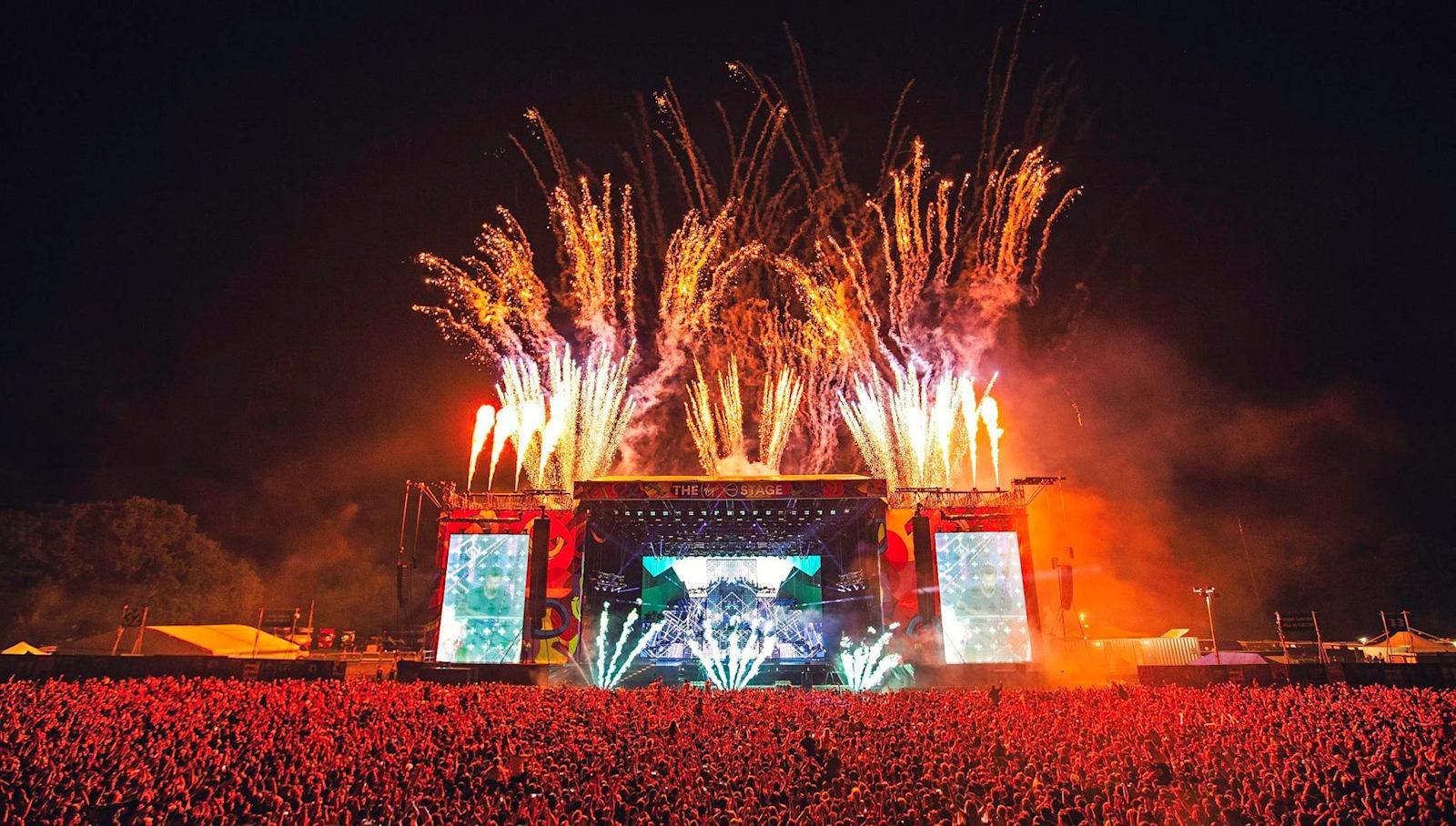 Festival main stage with fireworks above a large audience